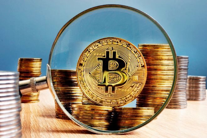 Moneda de bitcoin en una lupa.
