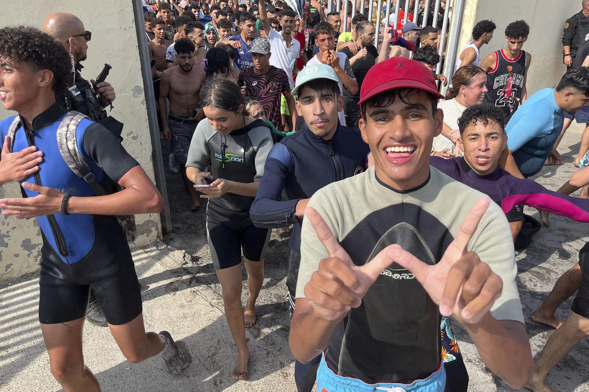 Varios j&oacute;venes saludan a c&aacute;mara tras cruzar la frontera de Espa&ntilde;a en Ceuta.
