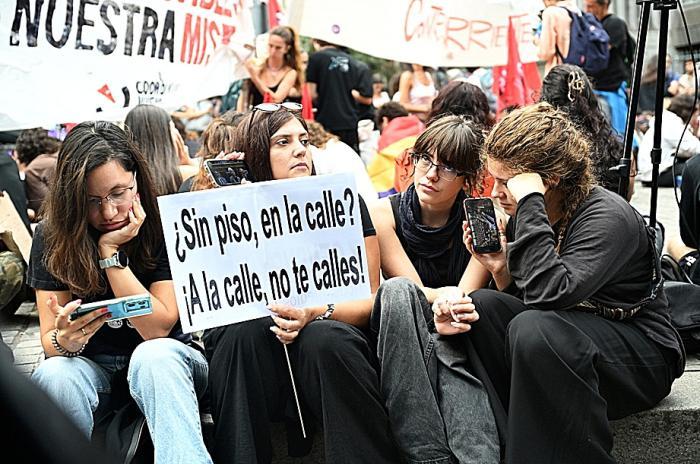 Varias personas siguen desde sus m�viles la votaci�n parlamentaria sobre los decretos de vivienda frente al Congreso de los Diputados el pasado 2 de octubre.